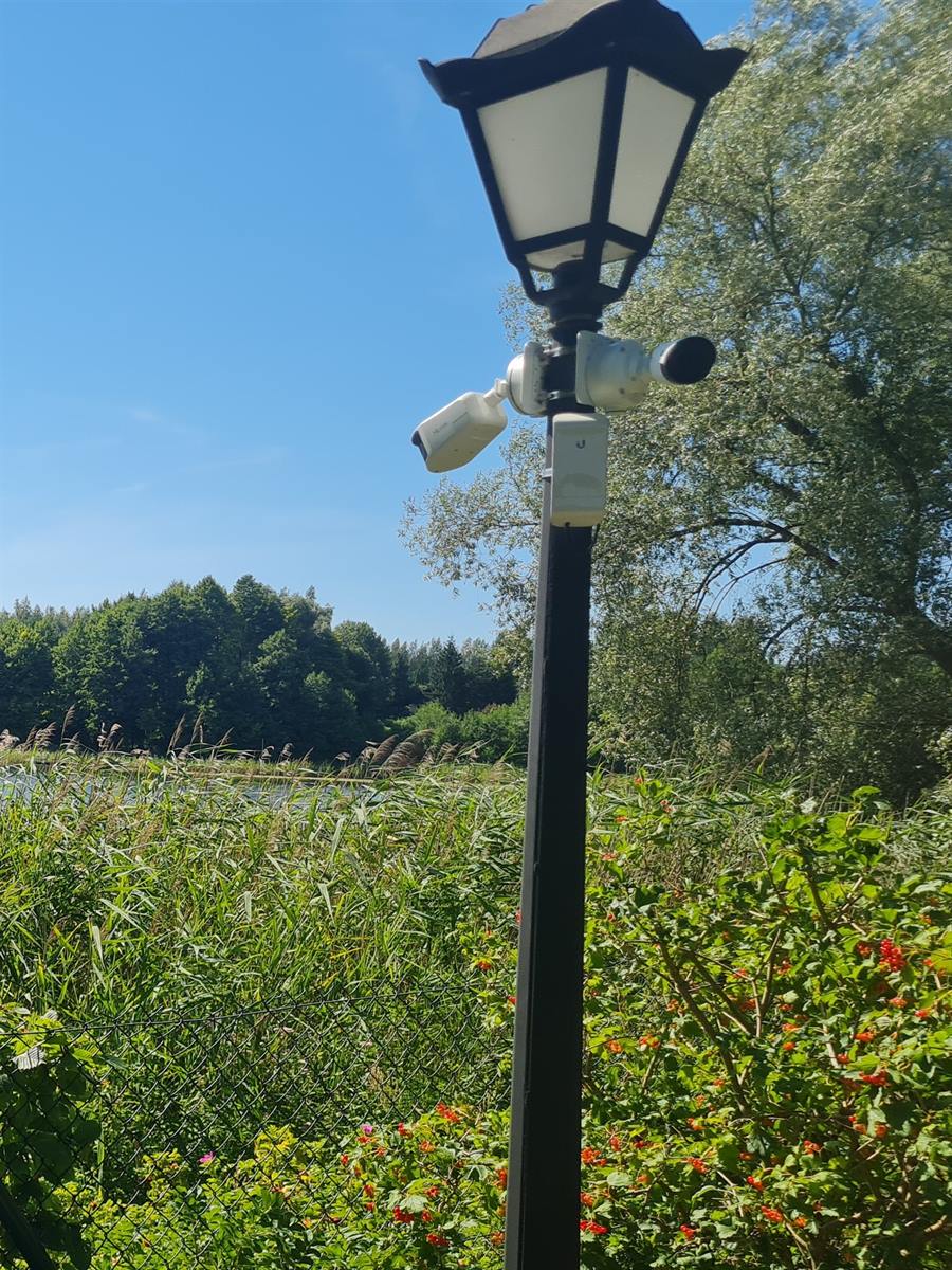 Kamery i punkt Wi-Fi Ubiquiti zamontowane na latarni na posesji nad jeziorem